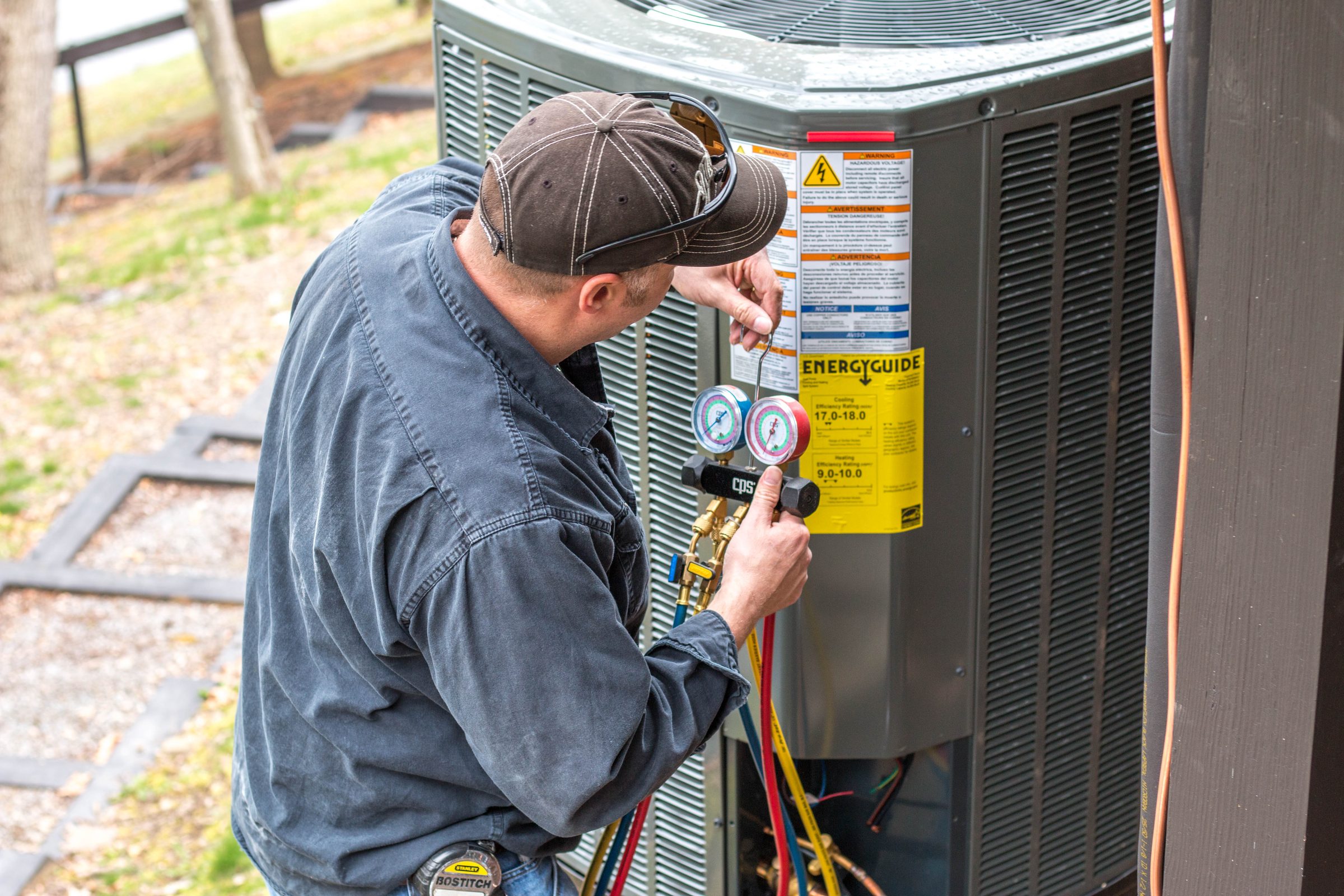 A Deep Creek Lake HVAC Solutions technician checking refrigerant pressures on a Trane outdoor unit